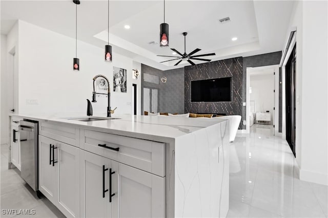 kitchen with open floor plan, a raised ceiling, light stone counters, a sink, and dishwasher