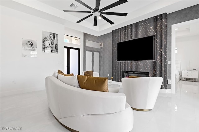 tiled living room featuring visible vents, a ceiling fan, baseboards, and a raised ceiling