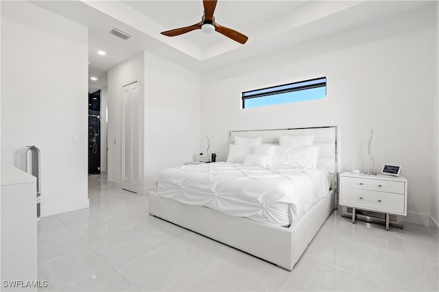 bedroom featuring visible vents, light tile patterned flooring, baseboards, a raised ceiling, and a ceiling fan