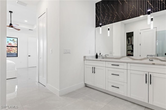 ensuite bathroom with connected bathroom, ceiling fan, double vanity, tile patterned floors, and baseboards