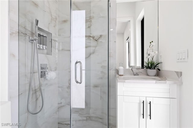 full bath with a marble finish shower and vanity