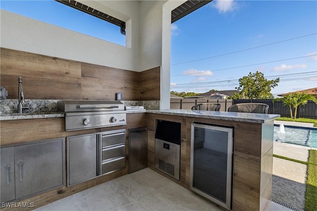 view of patio featuring grilling area, exterior kitchen, a sink, a fenced backyard, and beverage cooler
