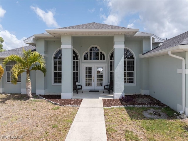 property entrance with french doors, a shingled roof, and stucco siding