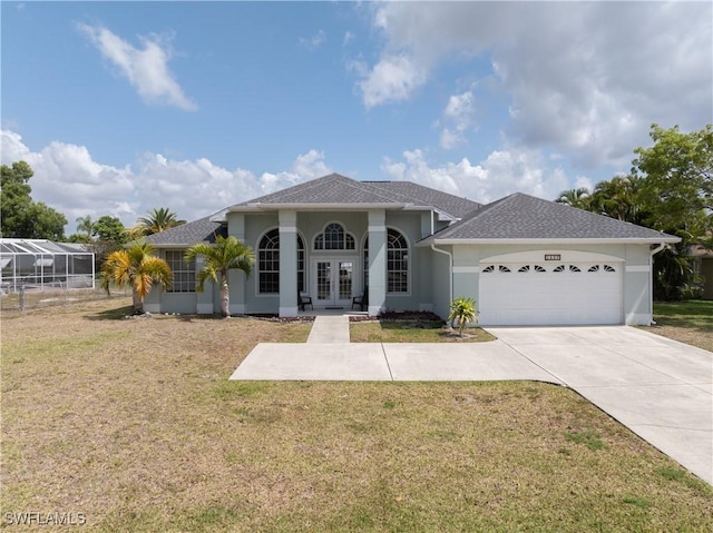 view of front of property with french doors, a front yard, driveway, and a garage