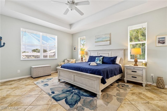 bedroom featuring a ceiling fan, baseboards, light tile patterned floors, and a raised ceiling
