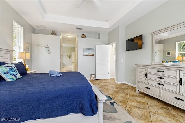 bedroom featuring connected bathroom, visible vents, and a raised ceiling