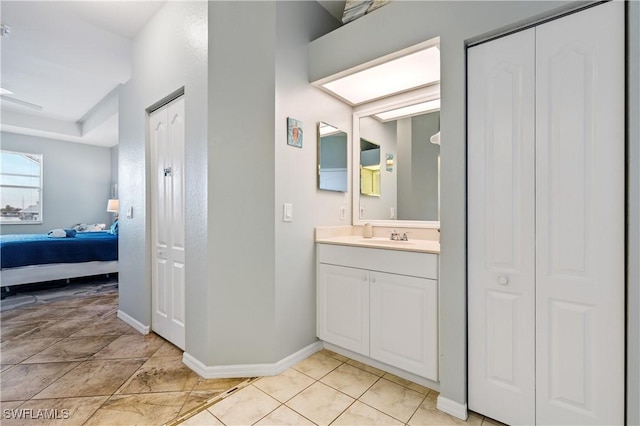 bathroom featuring vanity, baseboards, tile patterned floors, a closet, and ensuite bath