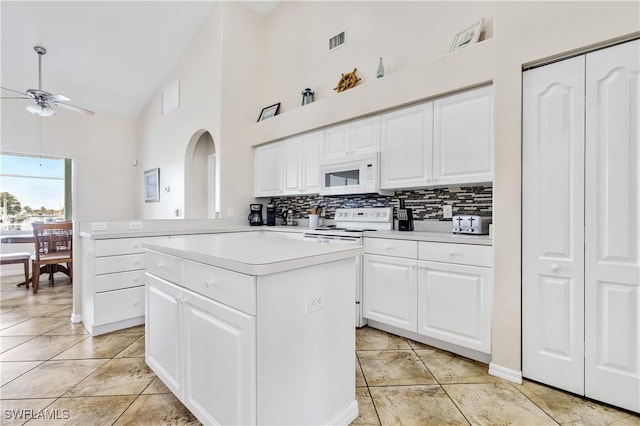 kitchen with white appliances, ceiling fan, light countertops, tasteful backsplash, and arched walkways