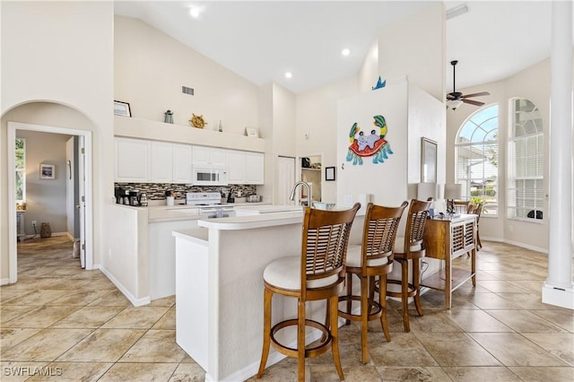 kitchen featuring ceiling fan, light countertops, high vaulted ceiling, white appliances, and white cabinetry