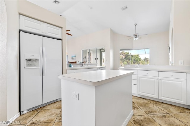kitchen featuring white cabinets, white refrigerator with ice dispenser, light countertops, a ceiling fan, and a kitchen island