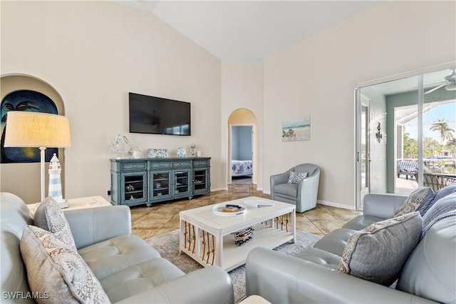 tiled living room featuring arched walkways, baseboards, vaulted ceiling, and ceiling fan