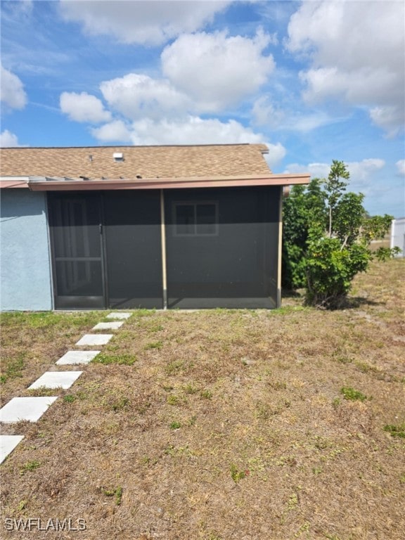 2123 NE 6th Pl, Cape Coral, FL 33909 - rear view of property featuring a sunroom, a shingled roof, a yard, and stucco siding