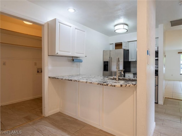 1228 SE 24th Ave Unit A, Cape Coral, FL 33990 - kitchen with stainless steel appliances, light stone counters, a peninsula, white cabinets, and baseboards