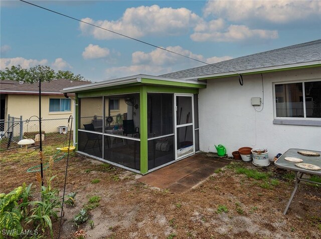 1228 SE 24th Ave Unit A, Cape Coral, FL 33990 - rear view of property with a sunroom, fence, stucco siding, and roof with shingles