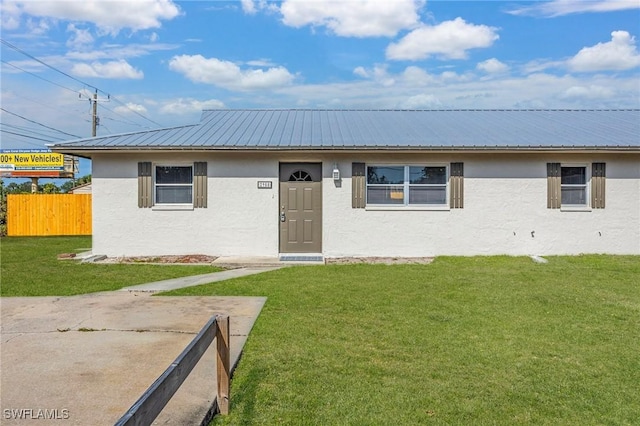 12955 First St, Fort Myers, FL 33905 - view of front facade featuring fence, metal roof, a front lawn, and stucco siding