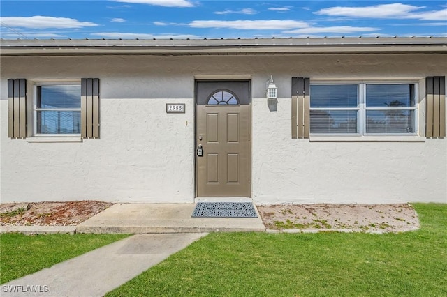 12955 First St, Fort Myers, FL 33905 - doorway to property with a lawn and stucco siding