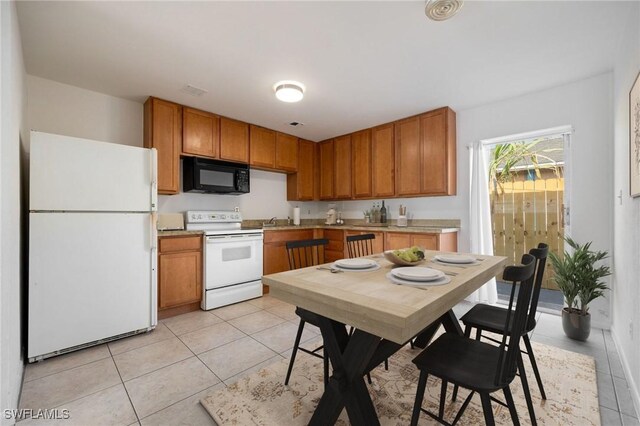12955 First St, Fort Myers, FL 33905 - kitchen with light tile patterned flooring, a sink, white appliances, light countertops, and brown cabinetry