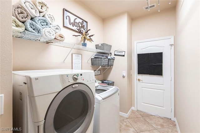 laundry area featuring laundry area, visible vents, light tile patterned flooring, baseboards, and independent washer and dryer
