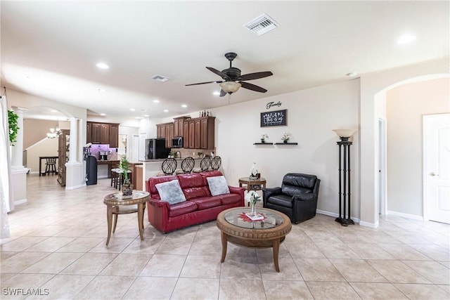 living area featuring arched walkways, a ceiling fan, ornate columns, and light tile patterned flooring