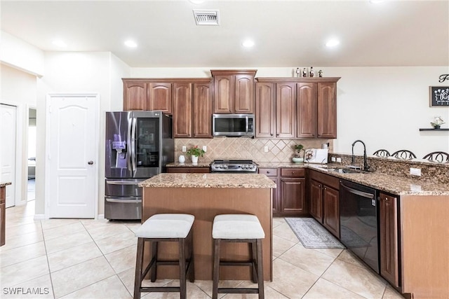 kitchen with visible vents, a sink, a peninsula, a breakfast bar, and stainless steel appliances