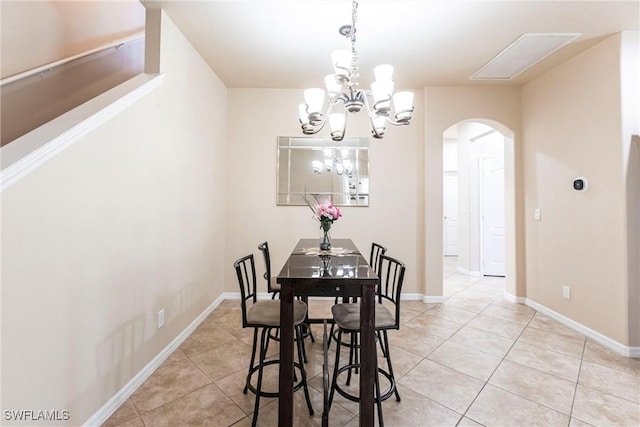dining area with arched walkways, baseboards, a chandelier, and light tile patterned floors