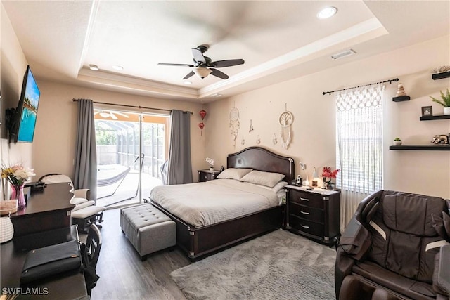bedroom featuring ceiling fan, access to exterior, wood finished floors, a tray ceiling, and recessed lighting