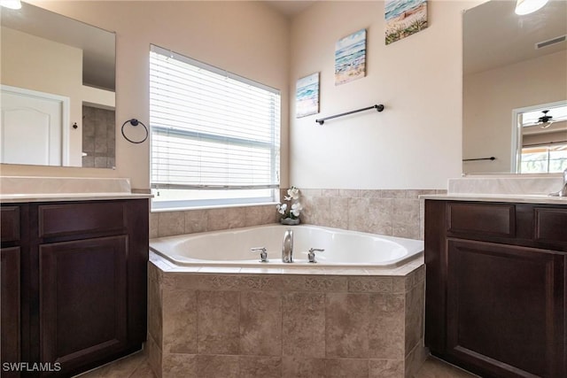 bathroom with tile patterned flooring, two vanities, a garden tub, and visible vents