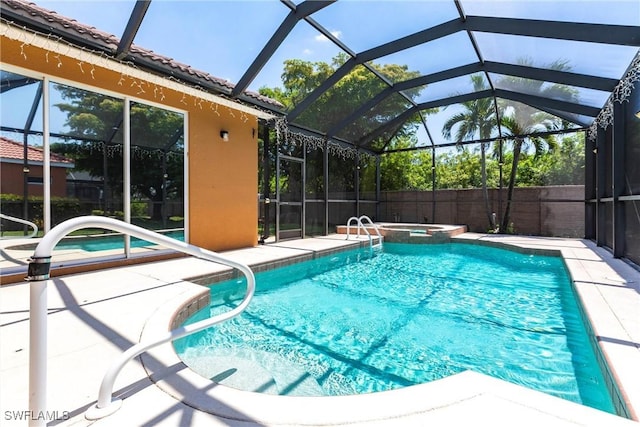 view of pool with glass enclosure, a patio area, and a pool with connected hot tub
