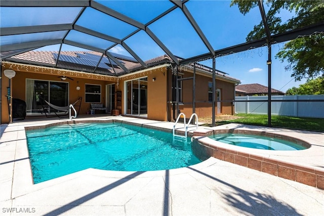 view of pool featuring a lanai, a ceiling fan, a pool with connected hot tub, fence, and a patio