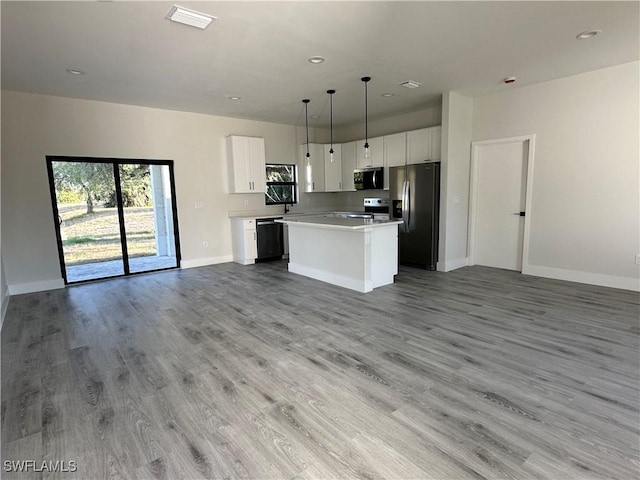 kitchen with appliances with stainless steel finishes, open floor plan, baseboards, a kitchen island, and visible vents