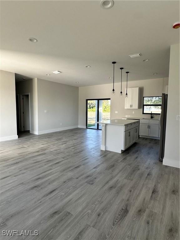 kitchen with a sink, baseboards, wood finished floors, and open floor plan