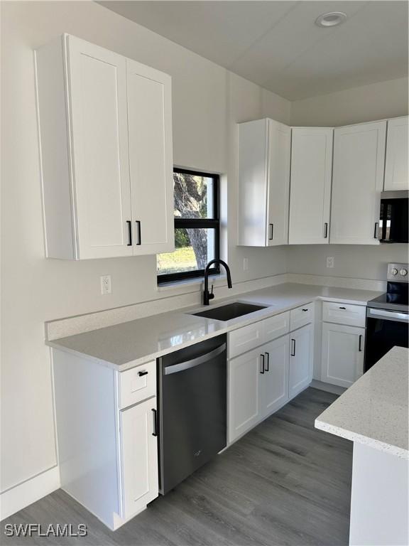 kitchen featuring a sink, white cabinets, stainless steel appliances, and dark wood-style floors