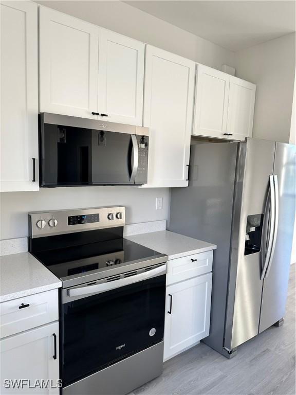 kitchen featuring light wood-style floors, light countertops, white cabinetry, and appliances with stainless steel finishes