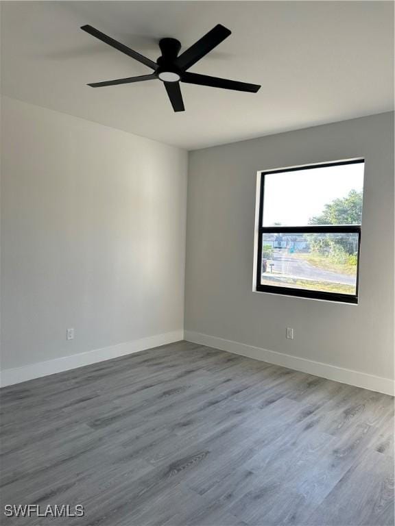 spare room with baseboards, a ceiling fan, and wood finished floors