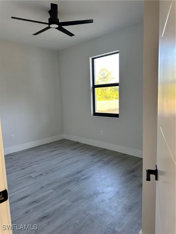 unfurnished room featuring baseboards, a ceiling fan, and wood finished floors