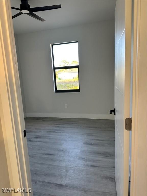 empty room with baseboards, ceiling fan, and wood finished floors