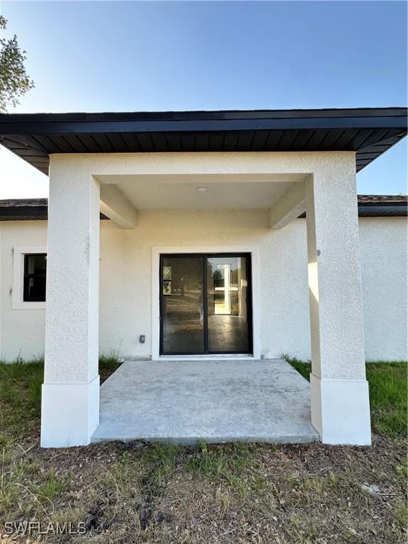 view of exterior entry featuring a patio and stucco siding