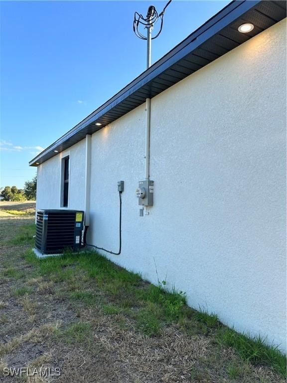 view of side of property featuring central AC and stucco siding