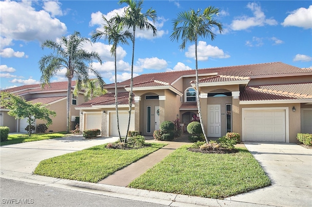mediterranean / spanish home with a tiled roof, stucco siding, driveway, and a front yard