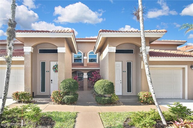 view of front of property with a tiled roof, an attached garage, driveway, and stucco siding