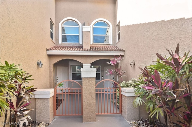 view of front of property featuring a gate, stucco siding, and a tile roof