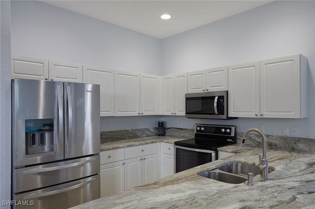 kitchen with a sink, white cabinets, light stone countertops, and stainless steel appliances