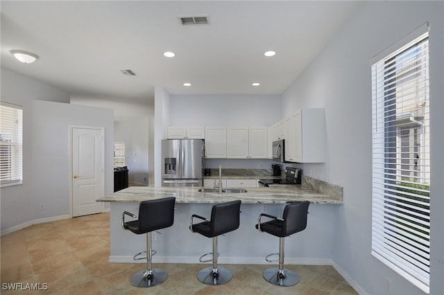 kitchen with a sink, stainless steel appliances, a peninsula, a healthy amount of sunlight, and visible vents