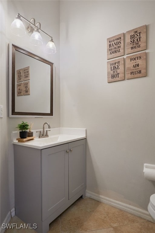 bathroom featuring baseboards, tile patterned flooring, toilet, and vanity
