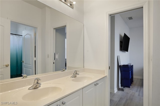 bathroom featuring double vanity, visible vents, a sink, and wood finished floors