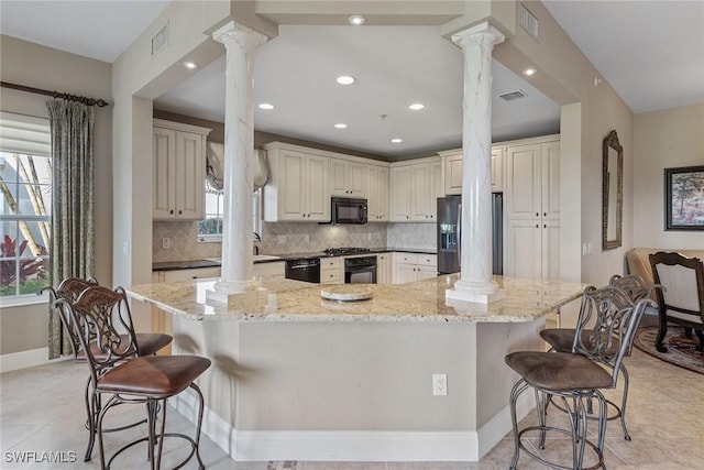 9030 Cascada Way Unit 102, Naples, FL 34114 - kitchen with ornate columns, a breakfast bar, and black appliances