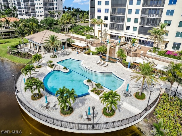 community pool featuring a patio area, fence, and a water view