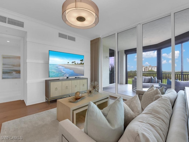 living room featuring wood finished floors, ornamental molding, and floor to ceiling windows