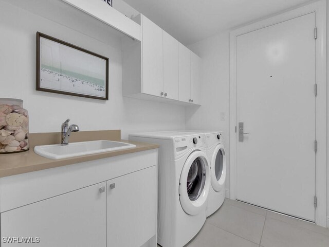 clothes washing area featuring cabinet space, washer and dryer, and light tile patterned floors