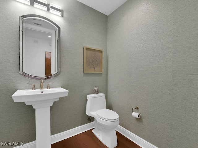 half bathroom featuring wood finished floors and toilet